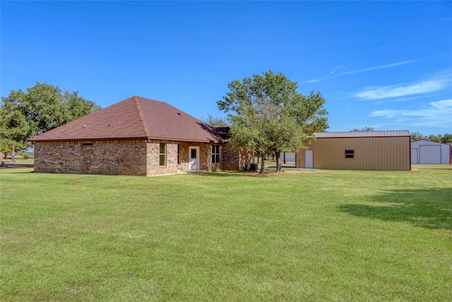 back of house featuring an outbuilding, a yard, brick siding, and a pole building