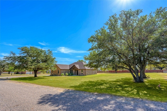 view of front of home with stone siding, fence, and a front yard