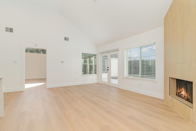 unfurnished living room with french doors, a fireplace, high vaulted ceiling, and light hardwood / wood-style flooring