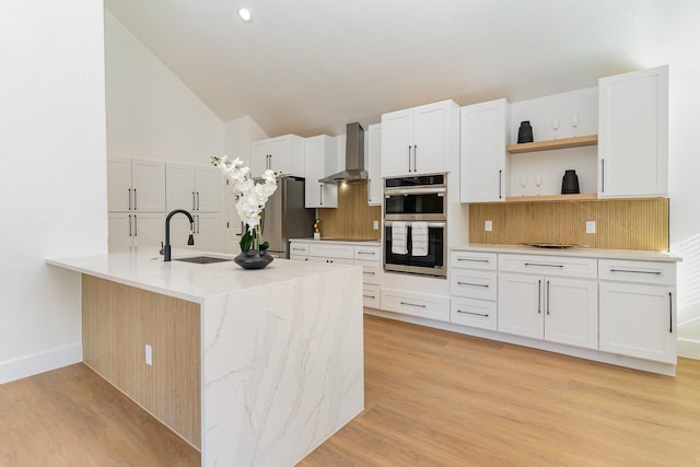 kitchen with white cabinetry, appliances with stainless steel finishes, wall chimney exhaust hood, and sink