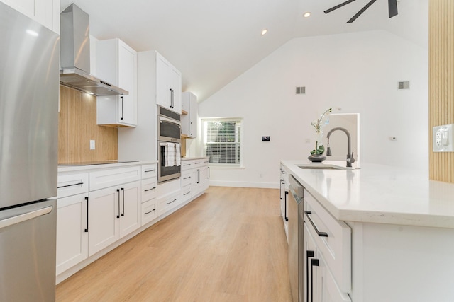 kitchen featuring lofted ceiling, white cabinets, light hardwood / wood-style floors, stainless steel appliances, and wall chimney range hood