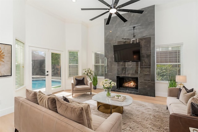 living room with french doors, crown molding, hardwood / wood-style floors, and a tile fireplace