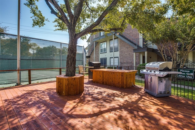 wooden deck with tennis court and grilling area