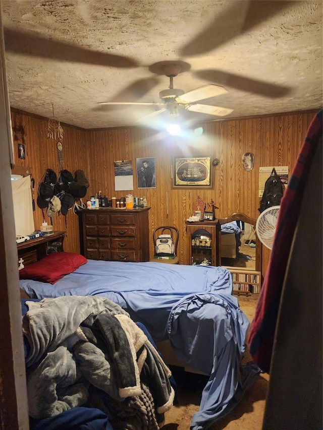 bedroom featuring ceiling fan, wood walls, and a textured ceiling