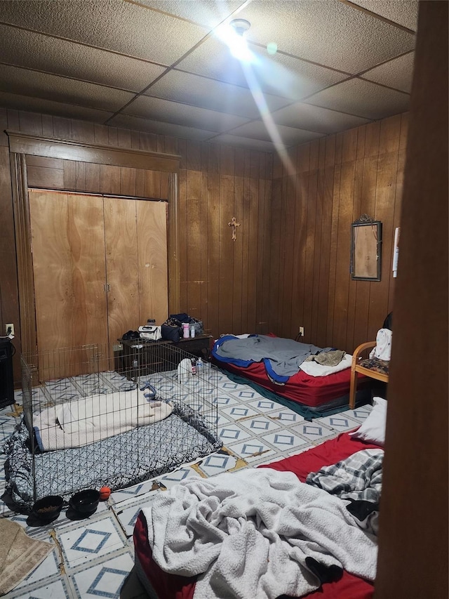 bedroom featuring wood walls and a paneled ceiling