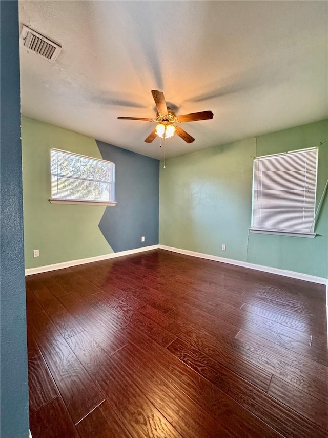 unfurnished room featuring baseboards, visible vents, ceiling fan, and wood finished floors