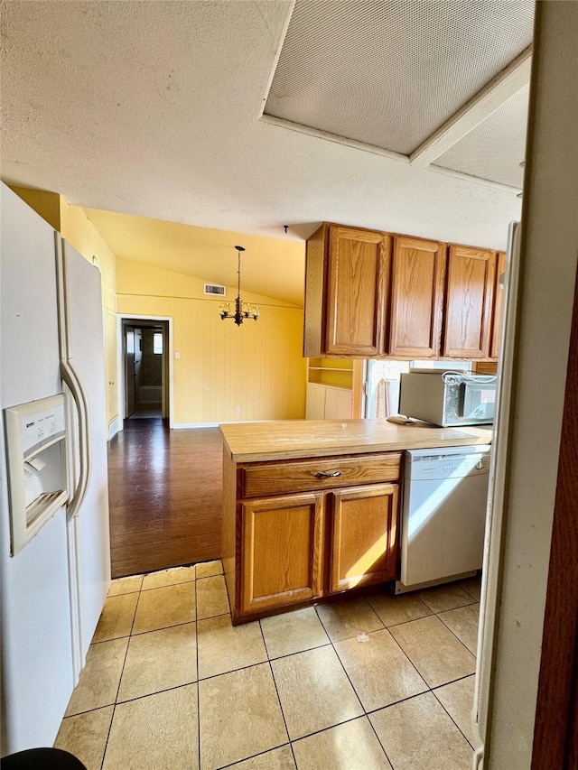 kitchen with light tile patterned floors, white appliances, visible vents, and brown cabinets