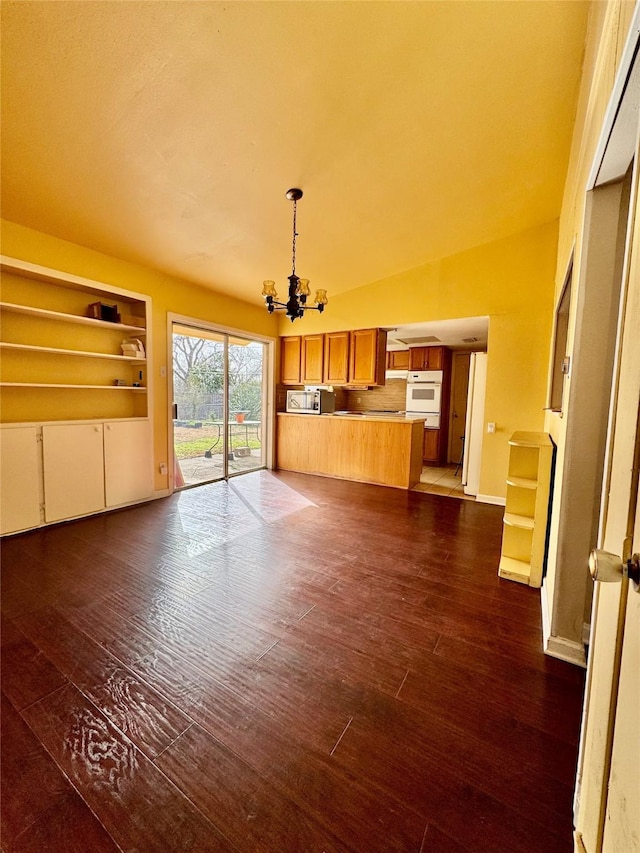 unfurnished living room with baseboards, dark wood-style flooring, and an inviting chandelier