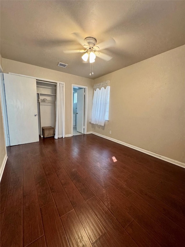 unfurnished bedroom featuring a textured ceiling, dark wood-type flooring, visible vents, and baseboards