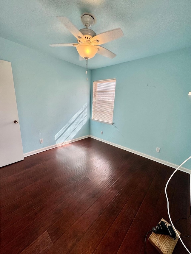 spare room featuring a ceiling fan, dark wood-style flooring, a textured ceiling, and baseboards