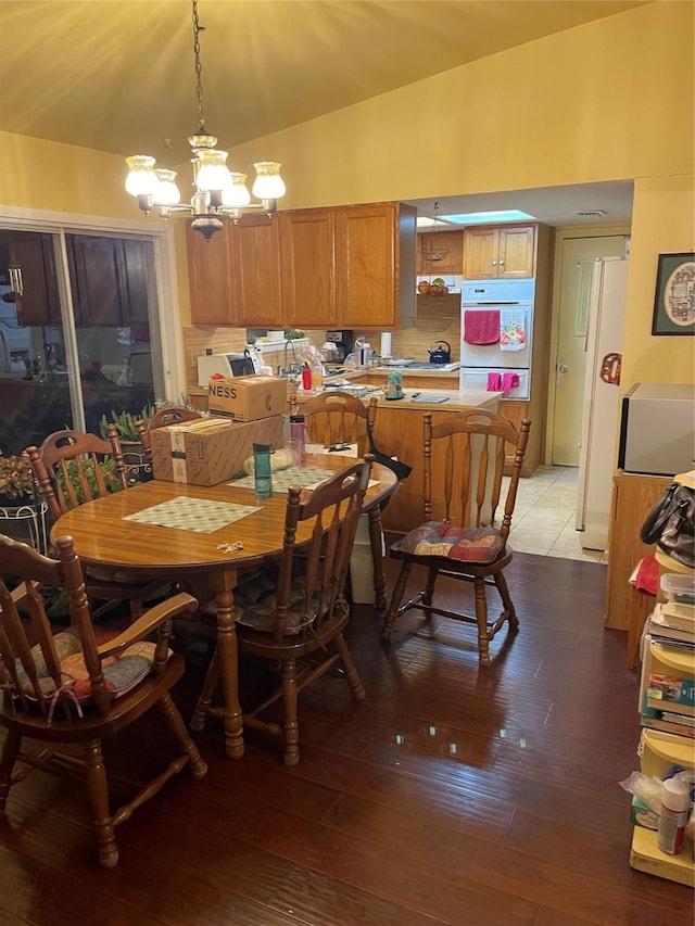 dining space with lofted ceiling, a chandelier, and light wood-type flooring