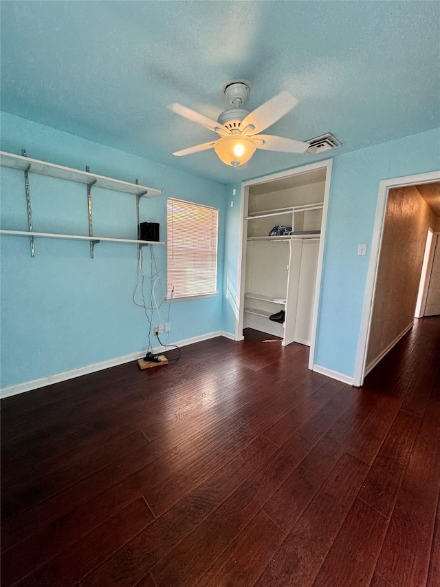 unfurnished bedroom featuring a closet, a textured ceiling, visible vents, and dark wood-style flooring