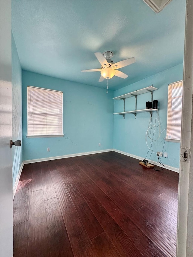 spare room featuring a wealth of natural light, ceiling fan, and dark wood-type flooring