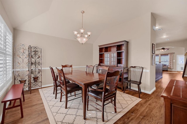 dining area with vaulted ceiling, ceiling fan with notable chandelier, and hardwood / wood-style flooring