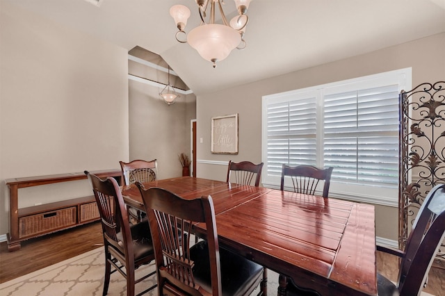 dining space with vaulted ceiling, a notable chandelier, and wood-type flooring