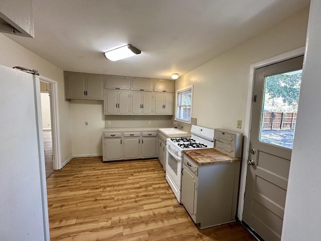 kitchen featuring white gas stove, gray cabinetry, light hardwood / wood-style flooring, and sink