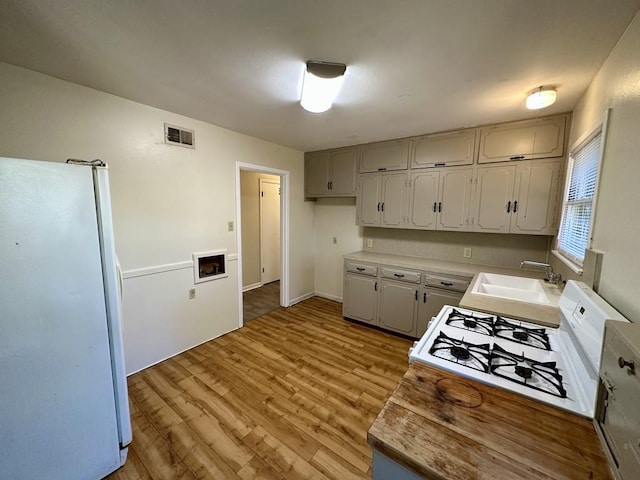 kitchen featuring gray cabinets, sink, hardwood / wood-style floors, and white appliances