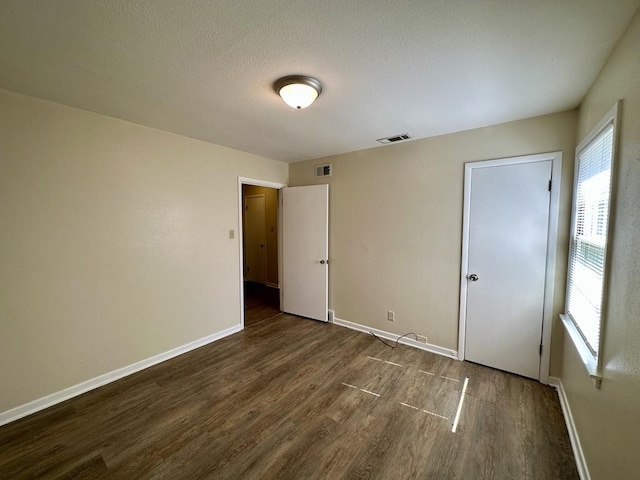 unfurnished bedroom featuring dark hardwood / wood-style flooring and multiple windows