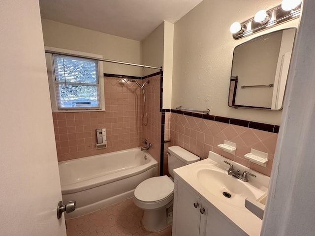 full bathroom with toilet, tiled shower / bath, tile walls, tile patterned floors, and vanity