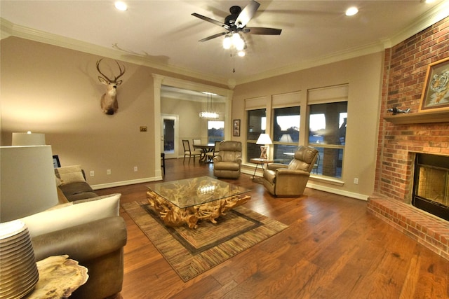 living room featuring a brick fireplace, dark hardwood / wood-style floors, ornamental molding, and ceiling fan