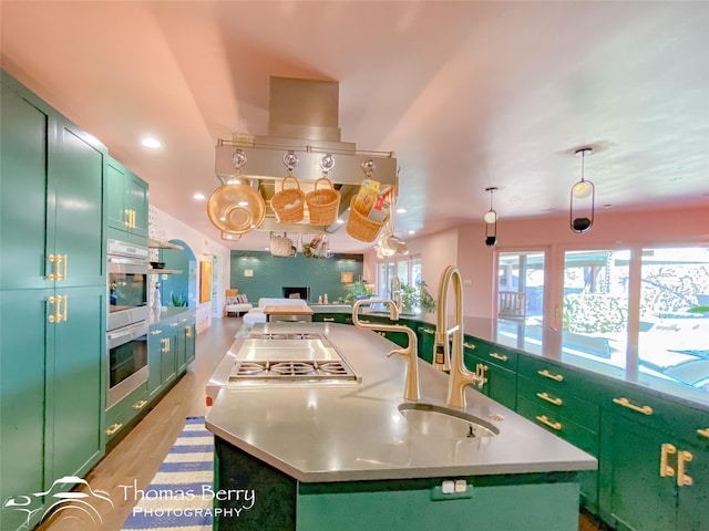 kitchen featuring a center island with sink, hanging light fixtures, and green cabinetry