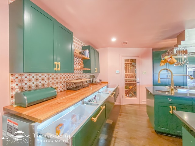 kitchen featuring tasteful backsplash, wooden counters, green cabinetry, and light hardwood / wood-style flooring