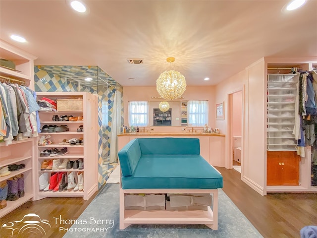 spacious closet with hardwood / wood-style flooring and an inviting chandelier