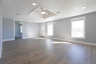 unfurnished room with ceiling fan, dark hardwood / wood-style flooring, and a raised ceiling