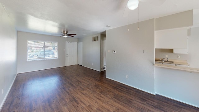 unfurnished living room with ceiling fan, sink, and dark hardwood / wood-style flooring