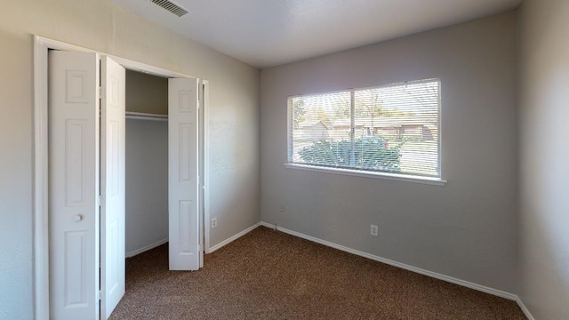 unfurnished bedroom featuring a closet and dark colored carpet