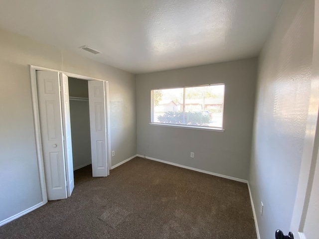 unfurnished bedroom featuring a closet and dark colored carpet