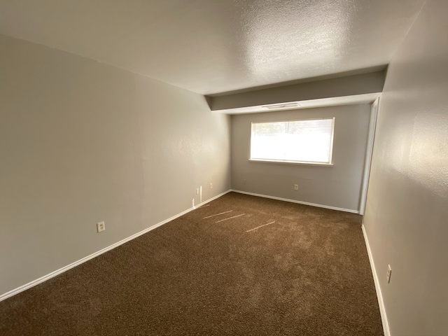 carpeted empty room with a textured ceiling