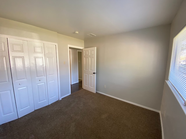 unfurnished bedroom featuring dark colored carpet and a closet