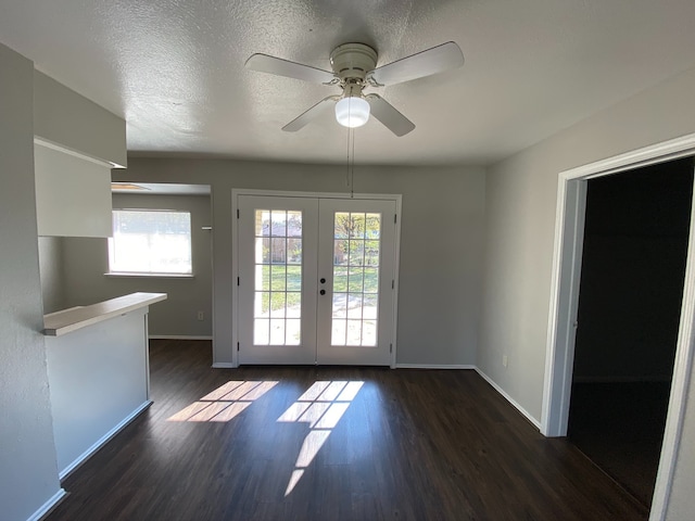 entryway with ceiling fan, dark wood-type flooring, french doors, and a textured ceiling