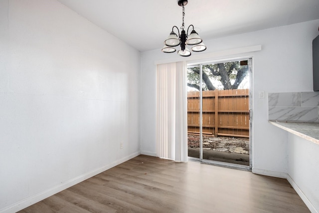 unfurnished dining area with a chandelier and hardwood / wood-style flooring