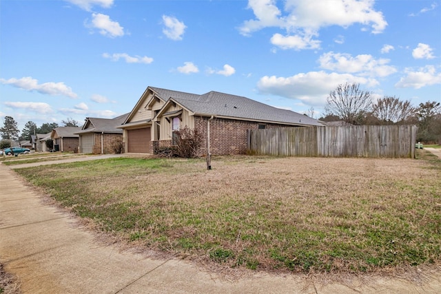 view of side of property with brick siding, a lawn, board and batten siding, fence, and a garage