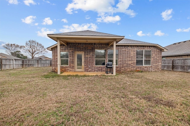 back of property featuring brick siding, a lawn, and a fenced backyard