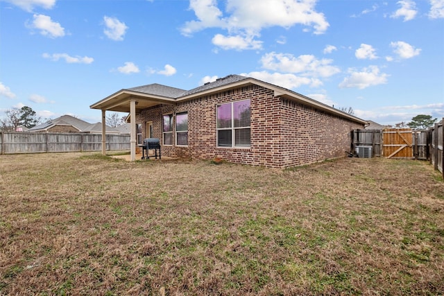 back of property with a yard, a fenced backyard, a gate, and brick siding