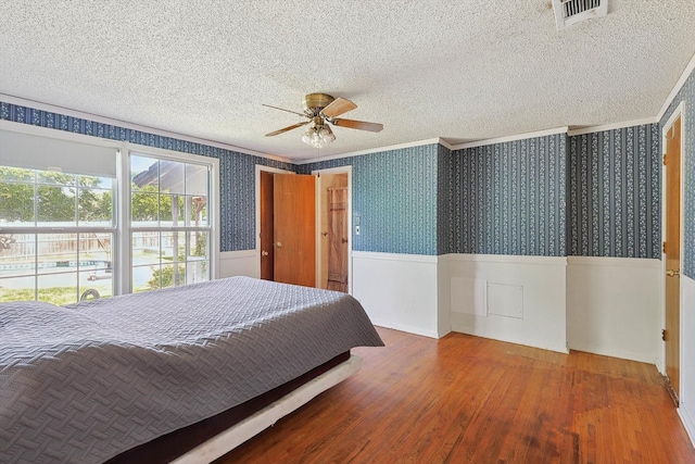 bedroom with crown molding, hardwood / wood-style flooring, a textured ceiling, and ceiling fan