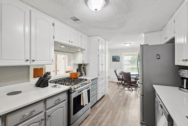 kitchen with light hardwood / wood-style floors, white cabinetry, decorative backsplash, and appliances with stainless steel finishes