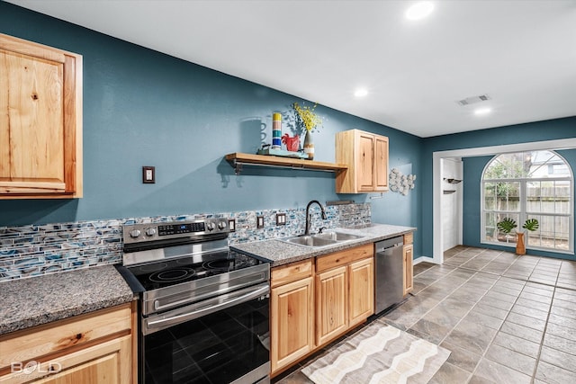 kitchen featuring stainless steel appliances, dark stone countertops, light brown cabinets, and sink