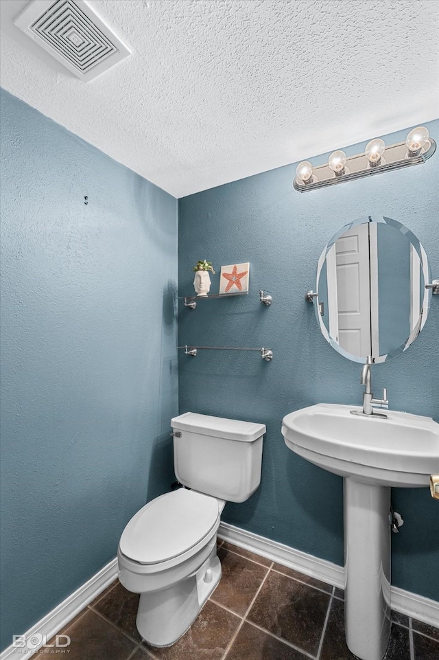 bathroom with toilet, tile patterned flooring, sink, and a textured ceiling