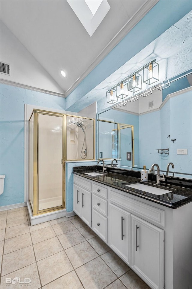 bathroom featuring a shower with door, vaulted ceiling with skylight, tile patterned floors, crown molding, and vanity