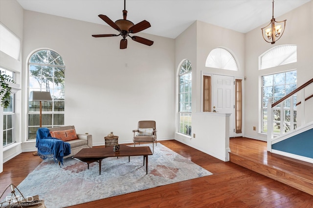 interior space featuring ceiling fan with notable chandelier, plenty of natural light, hardwood / wood-style floors, and a towering ceiling