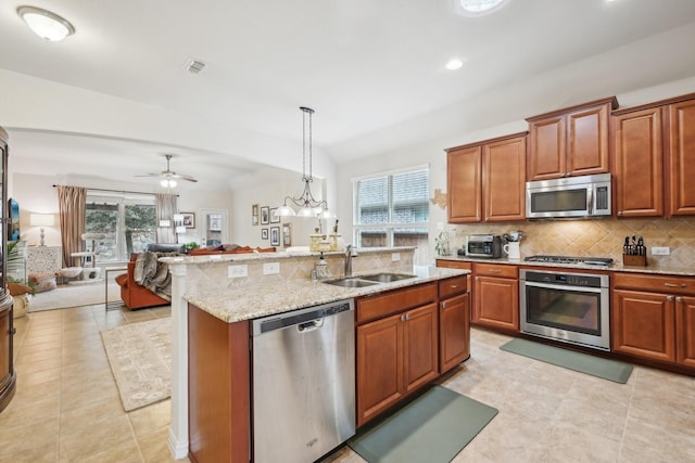 kitchen with appliances with stainless steel finishes, a kitchen island with sink, decorative light fixtures, a wealth of natural light, and sink