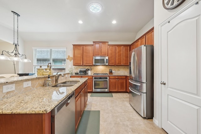 kitchen with appliances with stainless steel finishes, pendant lighting, light stone counters, and sink