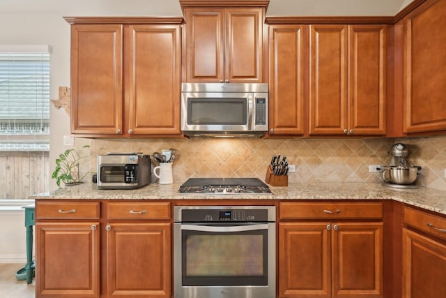 kitchen with light stone countertops, backsplash, and appliances with stainless steel finishes