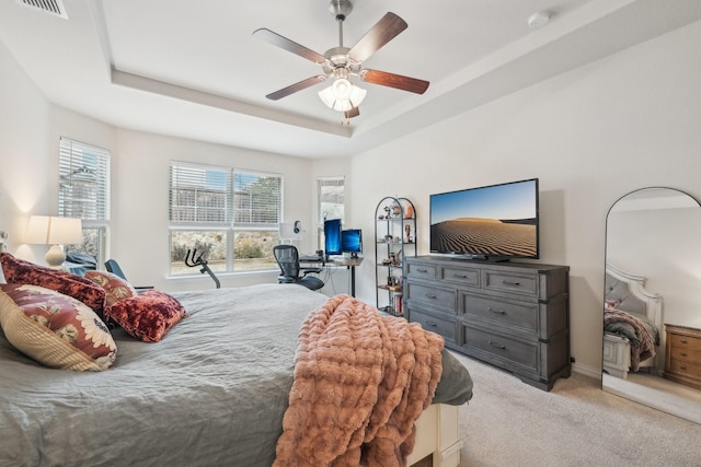 carpeted bedroom featuring ceiling fan and a tray ceiling