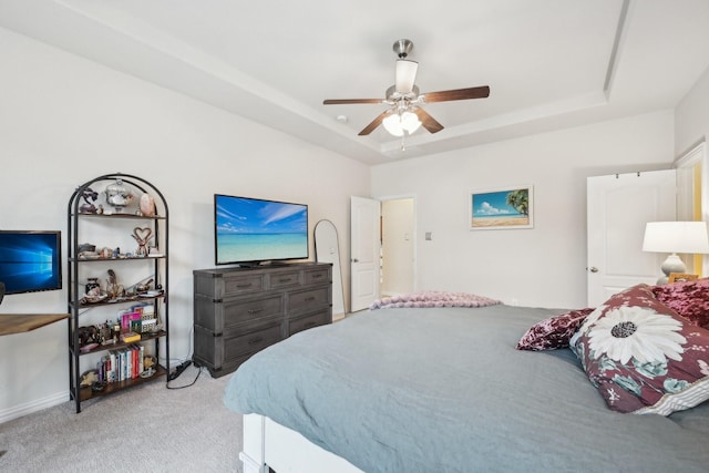 carpeted bedroom featuring ceiling fan and a tray ceiling