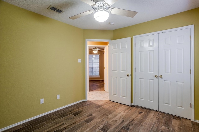 unfurnished bedroom featuring dark wood-type flooring, ceiling fan, a closet, and a textured ceiling